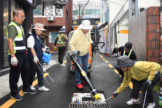 장준용 동래구청장이 16일 부산 동래구 명륜1번가 내 배수구, 빗물받이 등에 쌓인 담배꽁초 등을 새로 도입한 친환경 노면진공청소기로 제거하고 있다.