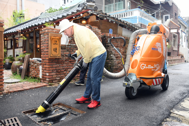 장준용 동래구청장이 16일 부산 동래구 명륜1번가 내 배수구, 빗물받이 등에 쌓인 담배꽁초 등을 새로 도입한 친환경 노면진공청소기로 제거하고 있다.