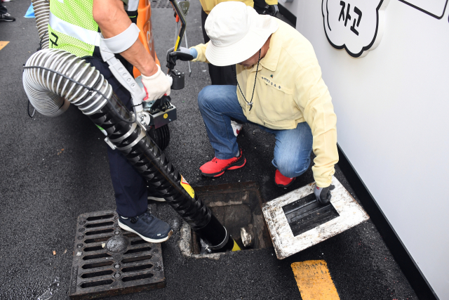 장준용 동래구청장이 16일 부산 동래구 명륜1번가 내 배수구, 빗물받이 등에 쌓인 담배꽁초 등을 새로 도입한 친환경 노면진공청소기로 제거하고 있다.