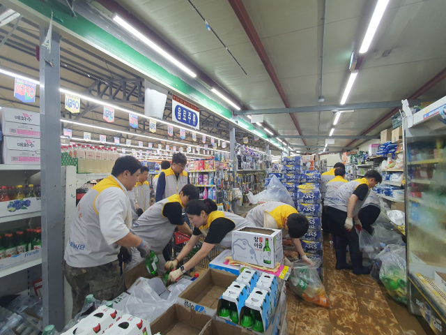 한국동서발전 당진발전본부와 협력사 직원들로 구성된 봉사단이 집중호우로 피해를 입은 당진전통시장 상가에서 조속한 영업 재개를 위해 물품을 정리하고 청소 작업을 하고 있다. 동서발전 제공
