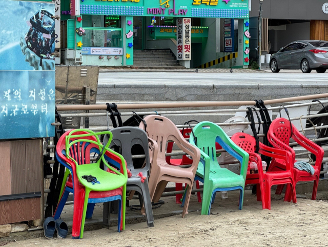 광안리 해변 난간에 자물쇠로 잠겨 늘어서 있는 플라스틱 의자들.