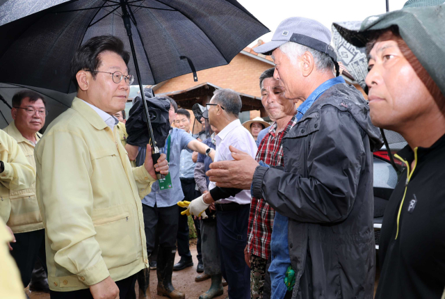 이재명 대통령이 21일 집중호우로 산사태가 발생한 경남 산청군 산청읍 부리마을에서 주민들을 만나 피해 상황 등에 대한 설명을 듣고 있다. 연합뉴스