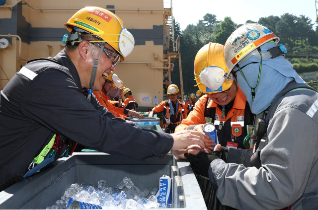 한화오션 김희철(왼쪽) 대표이사가 거제사업장 1독 주변에서 근로자들에게 음료와 쿨토시 등을 건네주고 있다. 한화오션 제공