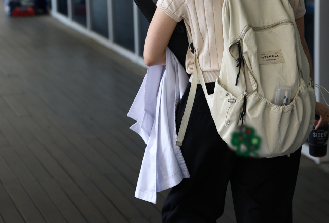 정부와 교육계가 '의대 교육 정상화 방안'을 논의하는 가운데 의대 총장들이 의대 본과 4학년이 추가로 의사국가시험(국시)를 치를 수 있도록 정부에 건의하기로 했다. 23일 서울 시내 한 의과대학에서 한 학생이 가운을 들고 걸어가고 있다. 연합뉴스