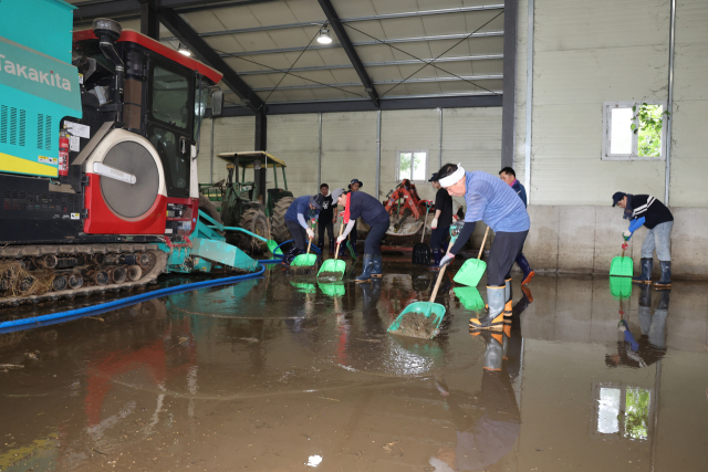 양산시 복구 지원단이 23일 침수 피해를 본 산청군 신안면의 한 농기계보관소를 청소하고 있다. 나동연 양산시장도 이날 지원단에 동참해 구슬땀을 흘리고 있다. 양산시 제공