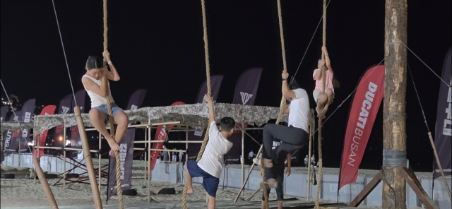 지난 25일 밤 9시께 부산 해운대구 해운대해수욕장 프로모션존 모습. 유격 훈련 체험 시설 '강철부대 체험존'에서 수직 줄 오르기를 시도하고 있는 참가자들의 모습. 박수빈 기자 bysue@