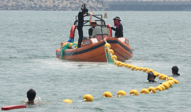 7월 해수욕장 개장을 앞두고 지난 6월 27일 오후 부산 수영구 광안리 해변에서 100m쯤 떨어진 수상 구역에서 구청 관계자가 해파리 차단 그물망을 설치하고 있다. 연합뉴스