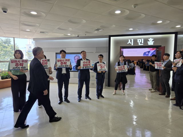 창원시 조명래 제2부시장이 31일 퇴임식에 참석하기 위해 복도를 걸어가고 있다. 퇴임식장 앞에서 여당 시의원들이 수사 중 퇴임을 규탄하는 시위를 진행했다.