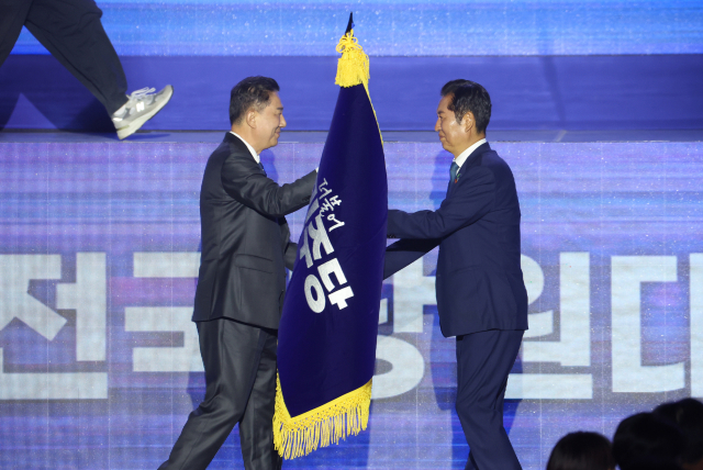 더불어민주당 정청래 신임 당대표가 2일 고양 킨텍스에서 열린 전국당원대회에서 김병기 당대표 직무대행 겸 원내대표로부터 당기를 이양받고 있다. 연합뉴스