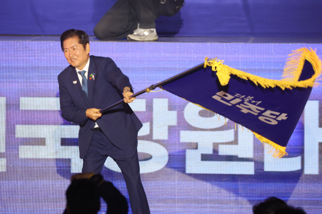 더불어민주당 정청래 신임 당대표가 2일 고양 킨텍스에서 열린 전국당원대회에서 김병기 당대표 직무대행 겸 원내대표로부터 받은 당기를 흔들고 있다. 연합뉴스