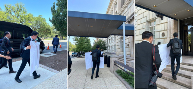 7월 24일(현지 시간) 워싱턴DC 미국 상무부 청사 앞에서 한국 협상단이 한미 관세 협상 타결에 결정적 돌파구 역할을 한 것으로 평가받는 '마스가'(MASGA) 프로젝트 설명 패널을 호텔 식탁보로 감싼 채 옮기고 있다. 연합뉴스