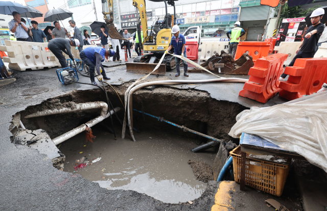 12일 부산 사상구 감전동 부산새벽시장 정문 앞에서 대형 싱크홀(땅 꺼짐 현상)이 발생해 관계기관들이 배수작업 등 긴급 복구 작업을 진행하고 있다. 이 사고로 소형 트럭 뒷바퀴가 빠졌으나 인명피해는 발생하지 않았다. 최근 부산도시철도 사상~하단선 공사 현장 인근에서 잇따라 싱크홀이 발생해 시민 불안감을 키우고 있다. 정종회 기자 jjh@