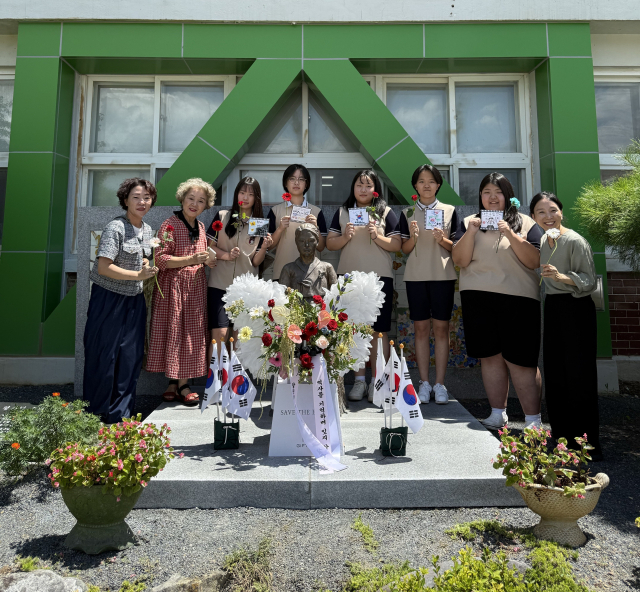 학교법인 명덕육영회 산하 함안여자중학교 학생들과 에코플라워협회 함안군 지부 관계자들이 14일 학교 내 소녀상(2019년도 건립)에서 역사 수업과 연계해 광복절 80주년 기념 교육 활동을 펼치고 있다. 함안여자중학교 제공