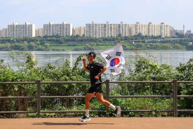 한국타이어가 후원하고 한국해비타트가 주관하는 ‘2025 815런’ 캠페인에서 가수 션이 태극기를 들고 달리고 있다.한국타이어 제공
