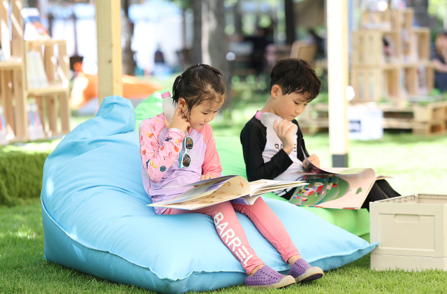 폭염이 이어진 지난 7월 29일 대구 수성구 수성패밀리파크에서 열린 '제9회 수성인문학제 수북수북 야외도서관' 행사에서 어린이들이 물놀이장 휴식 시간에 책을 보며 더위를 식히고 있다. 연합뉴스