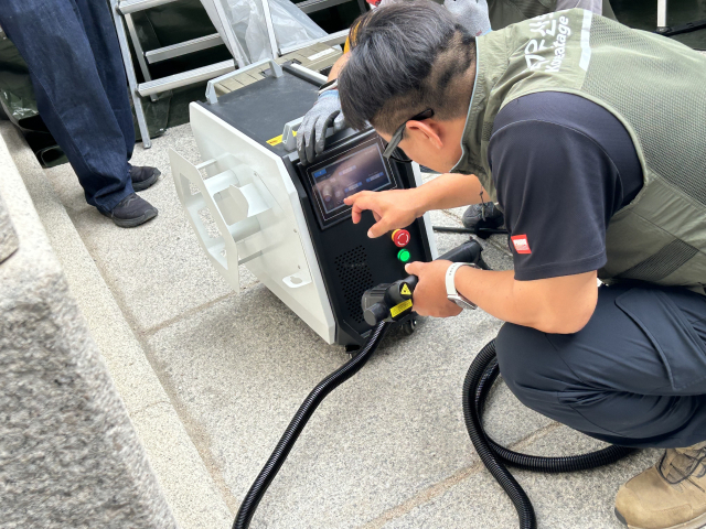11일 서울 경복궁 광화문 석축에 매직으로 쓴 낙서를 지우기 위해 문화유산 보존처리 업체 관계자들이 레이저 기기 작업을 준비하고 있다. 연합뉴스