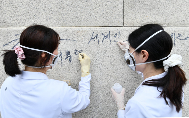 국립고궁박물관 유물과학과 관계자들이 11일 서울 경복궁 광화문 석축에 남은 낙서를 제거하고 있다. 국가유산청은 이날 오전 광화문 석축에 낙서를 한 79세 남성을 현장에서 확인해 경찰에 인계했다. 연합뉴스