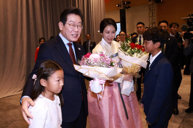 이재명 대통령과 김혜경 여사가 24일(현지 시간) 도널드 트럼프 미국 대통령과의 첫 정상회담을 앞두고 미국 워싱턴DC의 한 호텔에서 열린 동포 만찬 간담회에 참석해 화동으로부터 꽃다발을 받고 있다. 연합뉴스