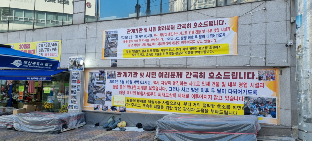 부산 북구 덕천동 노영태 씨가 운영하는 매장 앞에 붙은 현수막. 피해 보상이 미뤄지고 있는 상황을 호소하고 있다. 김준현 기자 joon@