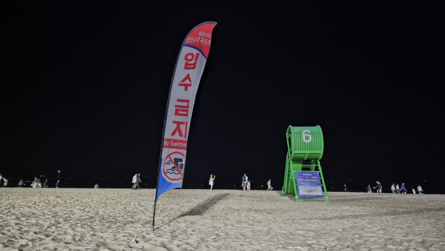 지난 25일 오후 9시께 부산 해운대해수욕장 모습. 해운대구 민간수상구조대는 오후 6시 퇴근에 맞춰 망루 뒷편에 입수 금지 배너를 설치한다. 해수욕장 개장 기간 입수 허용 시간은 매일 오전 9시부터 오후 6시까지로 제한돼 있다. 박수빈 기자