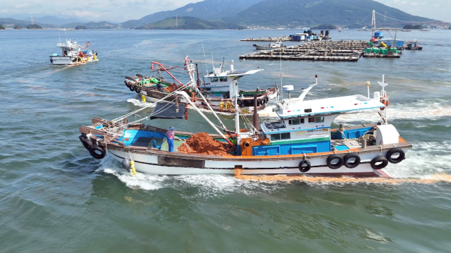 29일 경남 남해군 고현면 차면리 앞바다에서 어선이 빨간 적조 띠 주변으로 황토를 사용해 방제작업을 하고 있다. 독자 제공. 연합뉴스