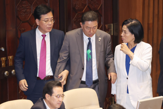 국민의힘 송언석 원내대표가 27일 국회 본회의장에서 더불어민주당 최민희 의원과 대화를 나누던 김병기 원내대표에게 다가가 손을 잡으며 말을 걸고 있다. 연합뉴스