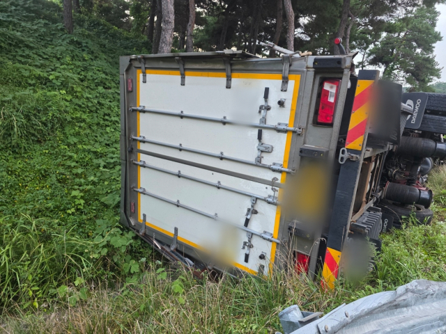 2일 오전 5시 55분께 부산 기장군 부산울산고속도로 장안IC 램프 구간에서 화물차량이 중앙 연석과 가드레일을 잇달아 들이받은 뒤 넘어졌다. 부산경찰청 고속도로순찰대 제공