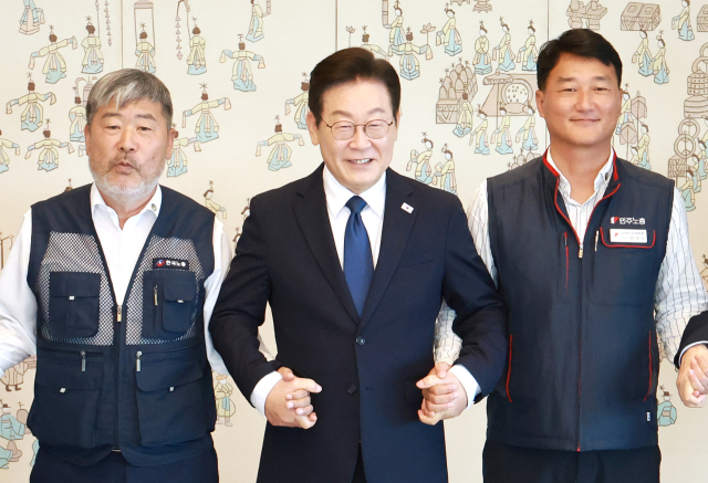 이재명 대통령이 지난 4일 서울 용산 대통령실 청사에서 열린 양대노총 위원장과의 오찬 간담회에 참석해 김동명 한국노총 위원장(왼쪽), 양경수 민주노총 위원장과 기념촬영을 하며 손을 잡고 있다. 연합뉴스