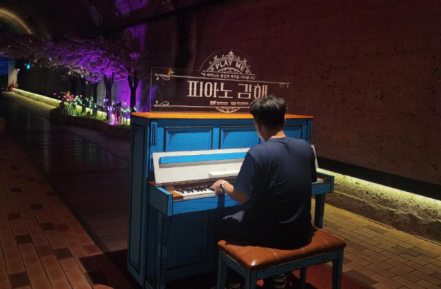 한 관광객이 김해낙동강레일파크 와인동굴에 설치된 ‘플레이 피아노’ 앞에 앉아 연주를 즐기고 있다. 김해시 제공