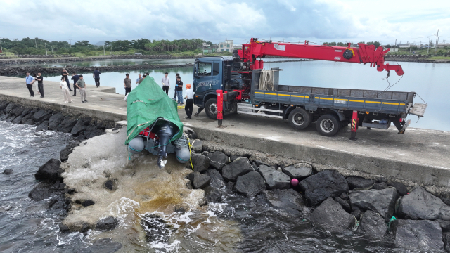 해경과 경찰 등 관계자들이 8일 오전 제주시 한경면 용수리 해안가에서 이날 오전 발견된 미확인 보트를 조사해 인양하려 하고 있다. 해경은 밀입국, 해양사고 등의 가능성을 열어 놓고 조사하고 있다고 밝혔다. 연합뉴스