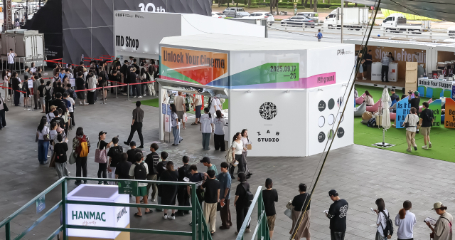 제30회 부산국제영화제 개막일인 17일 오전 부산 해운대구 영화의전당을 찾은 영화 팬들이 기념 굿즈를 사기 위해 긴 줄을 서 있다. 김종진 기자 kjj1761@