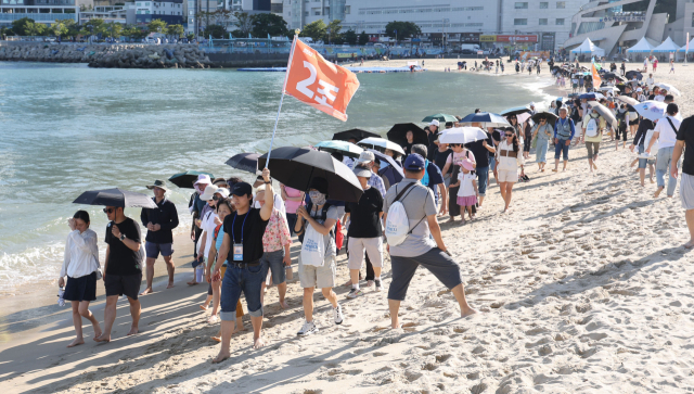 지난 20일 오후 부산 서구 송도해수욕장에서 열린 ‘맨발걷기 좋은 도시 부산 세븐비치 어싱 챌린지’ 행사에서 참가자들이 맨발로 바닷가를 걷고 있다. 이재찬 기자 chan@