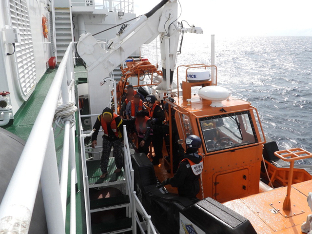 지난 19일 부산 송정 앞바다에 빠졌다가 인근 어선에 의해 구조된 어선 승선원들이 해경 경비정에 올라타고 있다. 연합뉴스