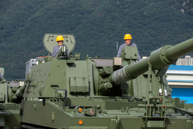 지난 19일 한화에어로스페이스 창원2사업장에서 진행된 ‘참전용사 재방한 행사’에서 미 해군의 병원선박인 ‘헤이븐(USS HAVEN)’에서 해군 간호사로 복무한 최고령 참석자 로이스 R. 귄(98, 왼쪽), 미 육군 하사로 참전한 로버트 M. 마르티네즈(94)가 K9 자주포에 탑승해 기념촬영하고 있다. 한화에어로스페이스 제공