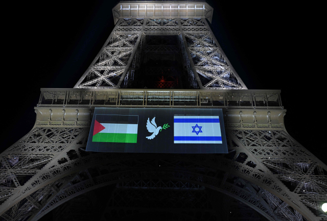 21일(현지 시간) 프랑스 파리 에펠탑에 설치된 대형 전광판에 팔레스타인(왼쪽)·이스라엘 국기와 평화를 상징하는 비둘기 문양이 함께 표시되고 있다. AFP연합뉴스
