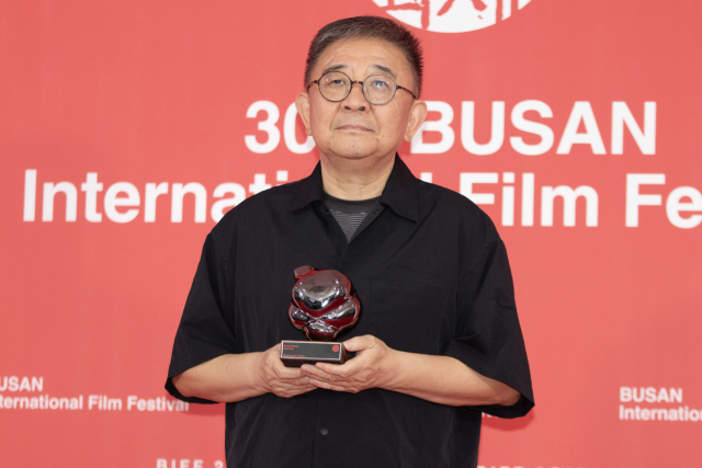 지난 26일 오후 부산 해운대구 영화의전당 야외무대에서 열린 제30회 부산국제영화제 폐막식에서 '루오무의 황혼'으로 경쟁부문 '부산 어워드' 대상을 거머쥔 장률 감독이 기자회견에 앞서 트로피를 들고 사진촬영에 임하고 있다. 정성운 인턴기자