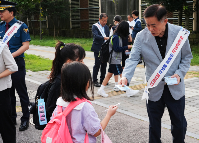 한전KPS 이성규 상임감사가 아동범죄 예방 홍보물품을 등교하는 학생들에게 배부하고 있다. 한전KPS 제공