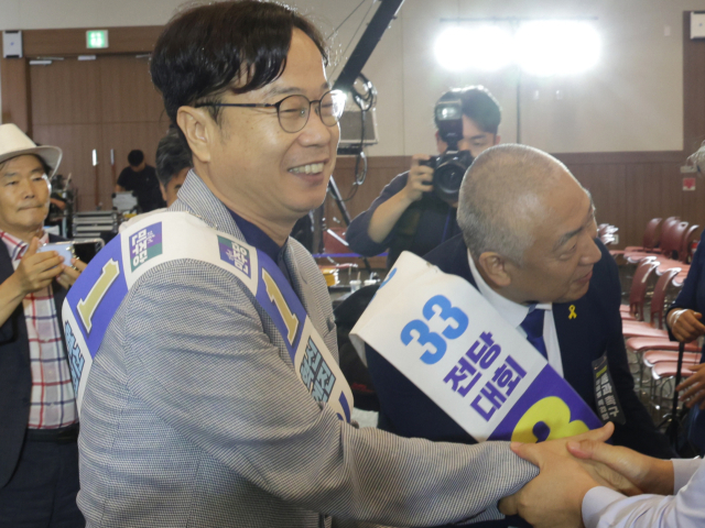 지난해 7월 27일 당시 신임 더불어민주당 부산시당위원장에 선출된 이재성(왼쪽) 시당위원장과 경선에서 낙선한 최택용 기장지역위원장이 참석자들과 악수하고 있다. 부산일보DB