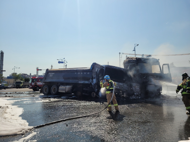 11일 울산 남구 용연사거리에서 덤프트럭과 트레일러가 충돌한 뒤 화재가 발생했다. 앞부분이 심하게 찌그러진 차량 주변으로 소방대원들이 불을 끄느라 분주하게 움직이고 있다. 울산소방본부 제공