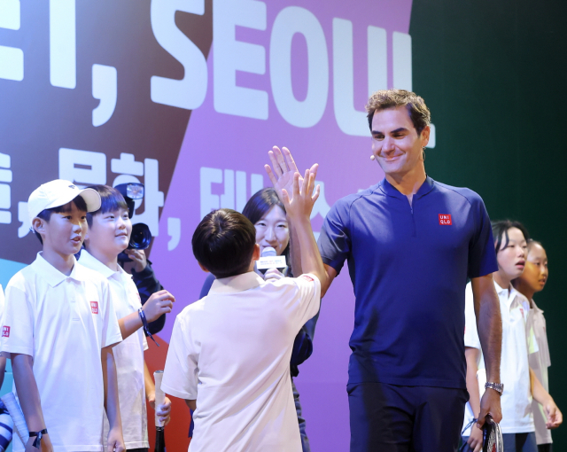 유니클로가 개최한 ‘로저 페더러와 함께하는 세계 여행’행사에서 테니스 전설 로저 페더러(오른쪽)이 유소년 선수와 하이파이브하고 있다. 유니클로 제