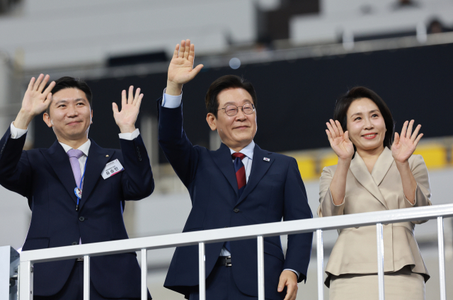 이재명 대통령과 김혜경 여사가 17일 부산 아시아드주경기장에서 열린 제106회 전국체육대회 개회식에서 입장하는 선수단을 향해 손을 흔들고 있다. 왼쪽은 유승민 대한체육회장. 연합뉴스