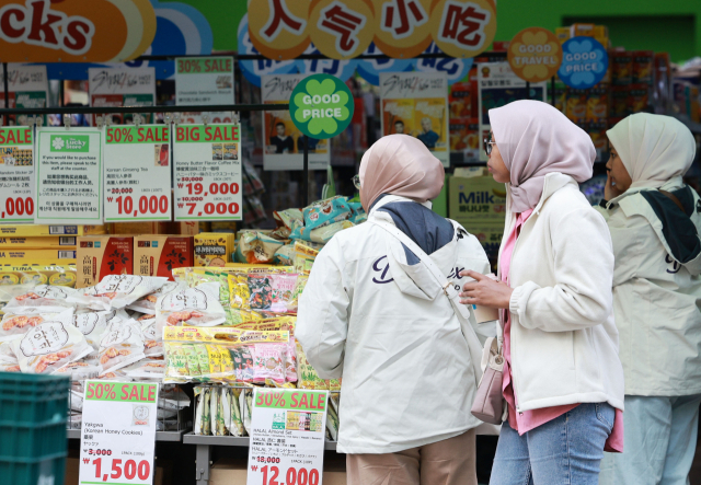 지난 20일 서울 명동의 한 마트에서 외국인 관광객들이 간식거리를 고르고 있다. 연합뉴스