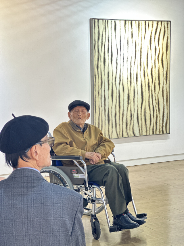 21일 금련산역갤러리에서 열린 ‘서재만 회고전: 묻혔습니다' 개막식에 휠체어를 타고 참석한 서재만 화백. 김은영 기자 key66@