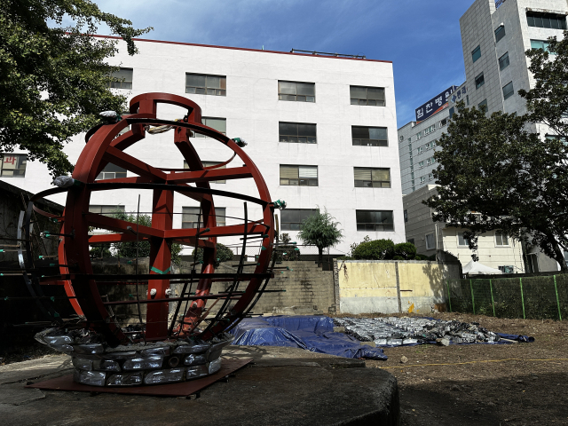 공장 건물 뒤편 전시장 입구에 세워져 있는 폐헤드라이트로 만든 달항아리 ‘환월 2025’ 골조. 전시 기간 틈틈이 작업을 완성할 예정이다. 김은영 기자key66@