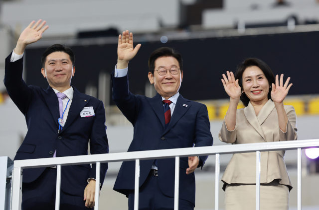 이재명 대통령과 김혜경 여사가 17일 부산 아시아드주경기장에서 열린 제106회 전국체육대회 개회식에서 입장하는 선수단을 향해 손을 흔들고 있다. 왼쪽은 유승민 대한체육회장. 연합뉴스