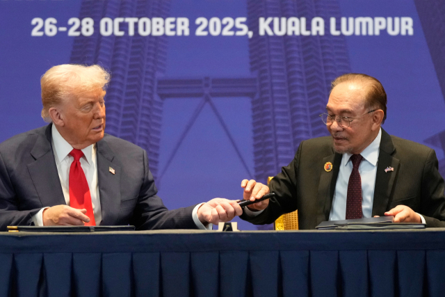 도널드 트럼프 미국 대통령이 26일(현지 시간) 말레이시아 쿠알라룸푸르에서 열린 아세안 정상회의 문서 서명식에서 안와르 이브라힘 말레이시아 총리에게 펜을 건네고 있다. AP연합뉴스