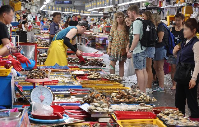 부산을 대표하는 수산물 시장이자 관광 명소인 자갈치현대화시장의 무상 사용 기간 종료를 앞두고 부산시와 상인 단체가 논의에 나선다. 사진은 지난해 8월 21일 오후 자갈치현대화시장에서 외국인 관광객들이 시장을 둘러보며 수산물을 고르는 모습. 부산일보DB