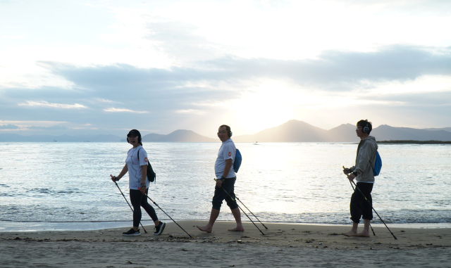 고도비만 환자가 비만대사 수술 이후 감량된 체중을 유지하기 위해선 규칙적인 운동과 식이조절이 중요하다. 고신대병원 외과 서경원(가운데) 교수가 부산 다대포 해수욕장 백사장에서 석양이 질 무렵 맨발로 노르딕 워킹을 하고 있다.