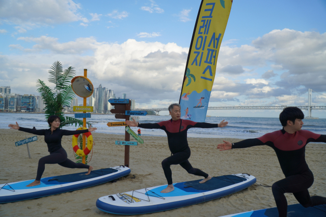 부정교합은 턱을 괴거나 한쪽으로만 씹는 습관 등이 원인이기 때문에 잘못된 자세와 습관 개선이 병행돼야 한다. 이루미치과 전영진(가운데) 원장이 부산 광안리 해변에서 SUP(서서 타는 패들보트)와 요가를 동시에 즐기는 SUP 요가를 체험하고 있다.