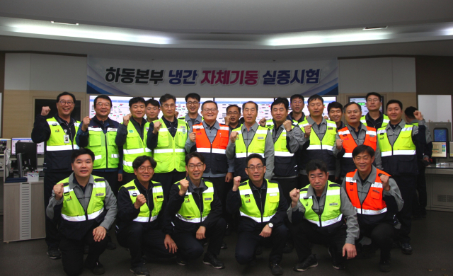 한국남부발전 하동빛드림본부 윤상옥 본부장(두 번째 줄 가운데 주황색 조끼)과 기술원들이 하동본부 중앙제어실에서 자체기동 실증시험을 성공적으로 수행한 후, 기념촬영을 하고 있다. 남부발전 제공